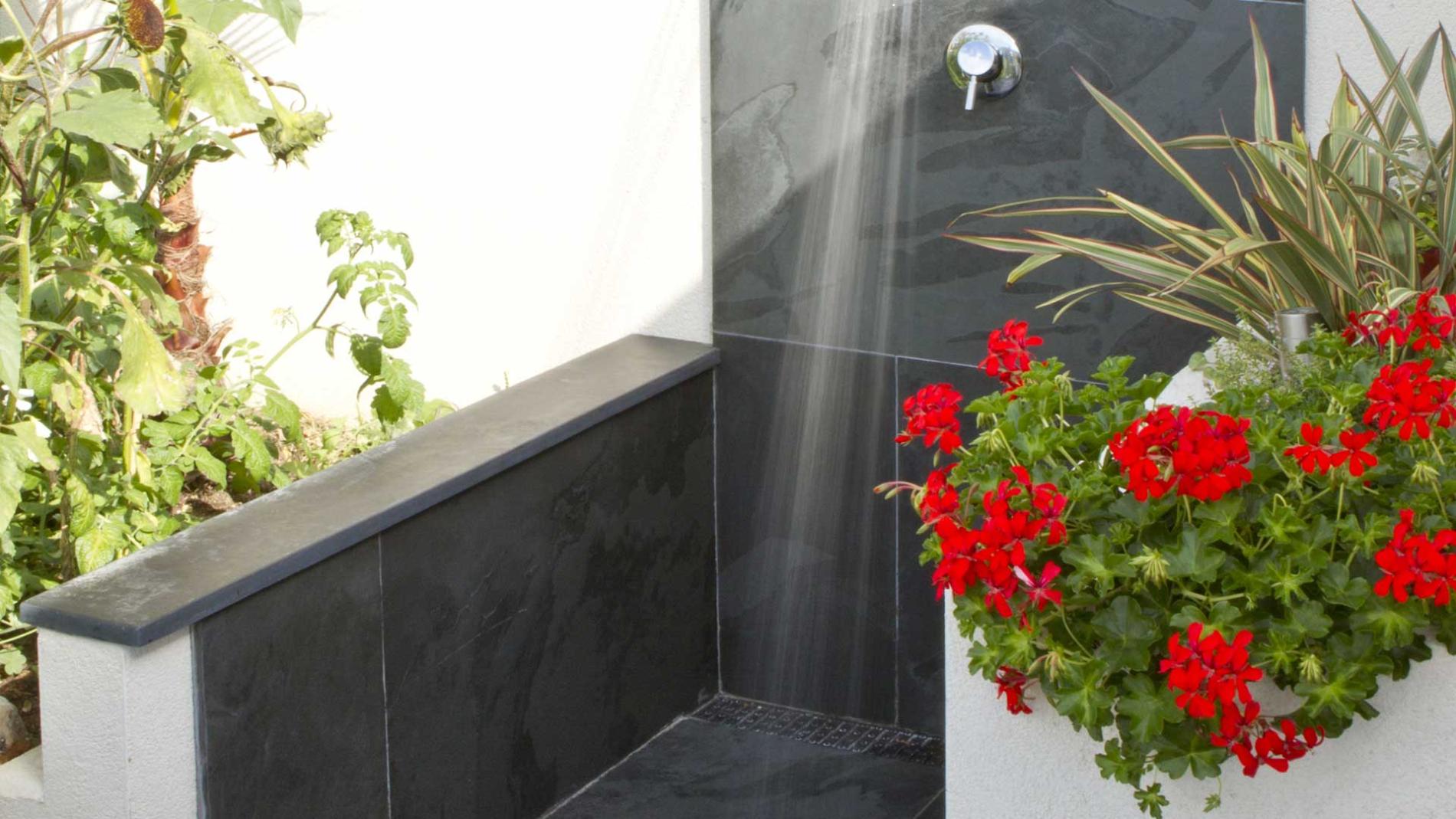 An Outdoor Shower with Slate Floor & Wall Tiles Surrounded by Brightly Coloured Plants