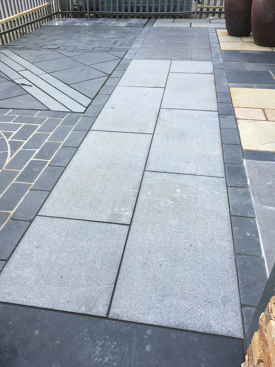 paving with light grey and dark grey paving slabs in various patterns