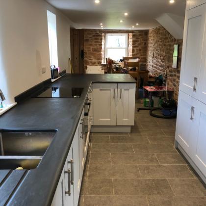 Exposed stone wall at rear of kitchen with slate worktop
