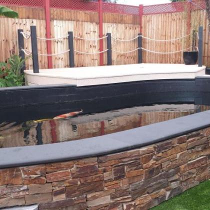 stone cladding and aged edge slate capping koi pond
