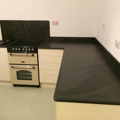 L shaped kitchen with slate splashback and worktops with smooth edging