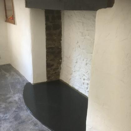 Narrow slate fire hearth with smoothed edges in semi circle design
