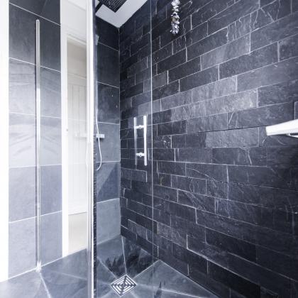 Modern glass shower with rough wall tiles cut from slate