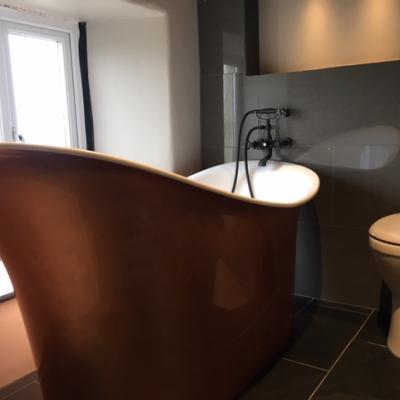 Large copper contemporary bath in a stunning modern bathroom with slate tiles
