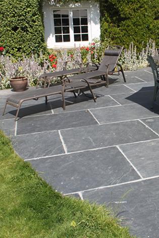 Patio in cottage garden with large rectangular slate flagstones