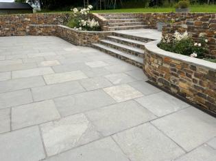 rectangular lime ash tiles in a large garden patio with steps to the lawn