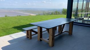 Alte and solid wood table and single pew bench overlooking the sea