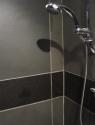Slate shower panels in black and grey tiles with a chrome head piece