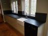 Sunken Belfast sink in a galley kitchen with slate worktop with cream units and black oven