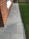 lime ash tiles in a garden path around a house with slate cobbled edging