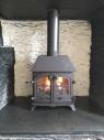 Lit fire in a woodburner in a traditional inglenook fireplace